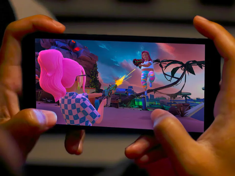 A person holding a phone horizontally while playing a colorful mobile action game