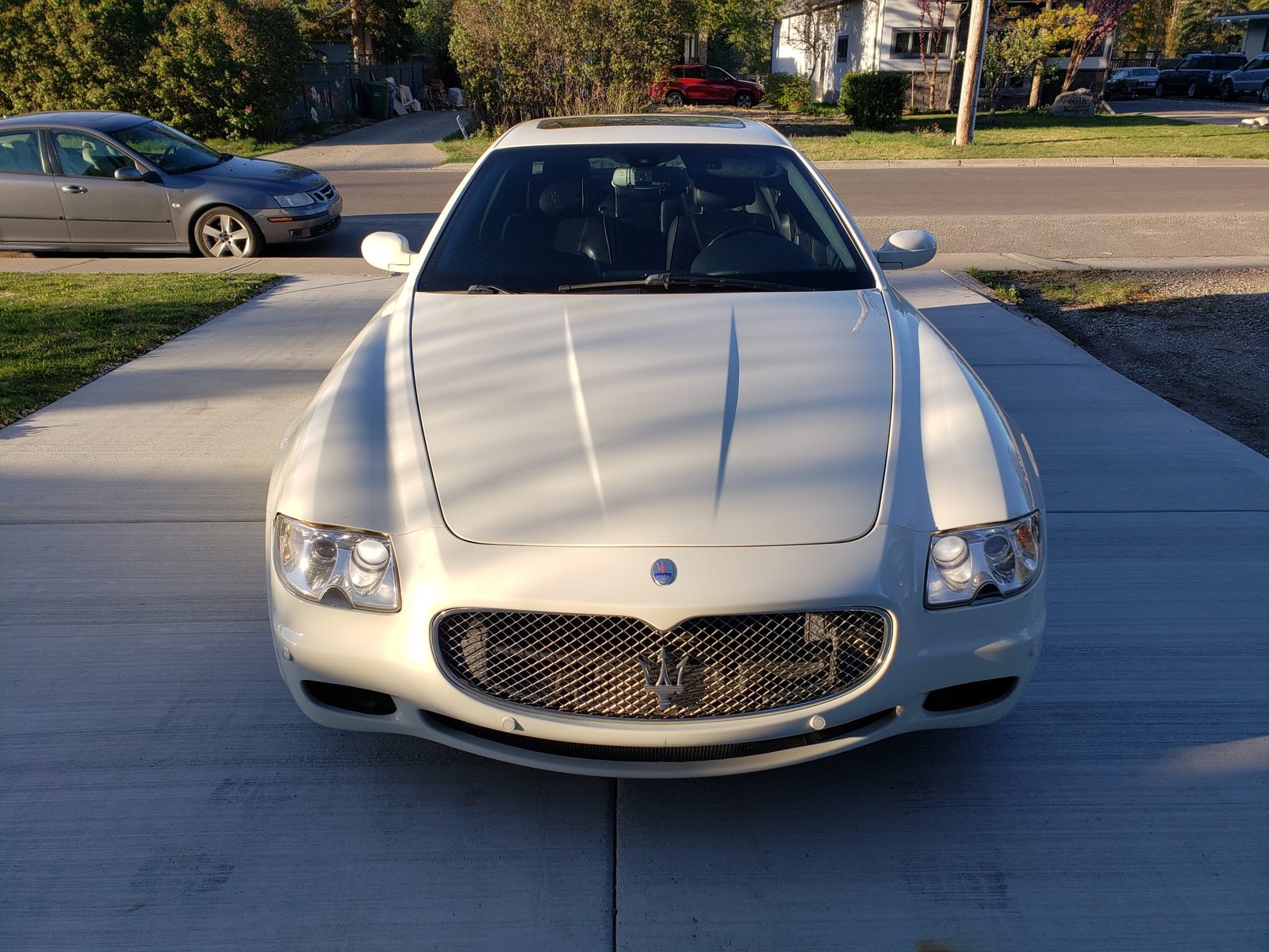 White Maserati Quattroporte on a residential driveway at golden hour