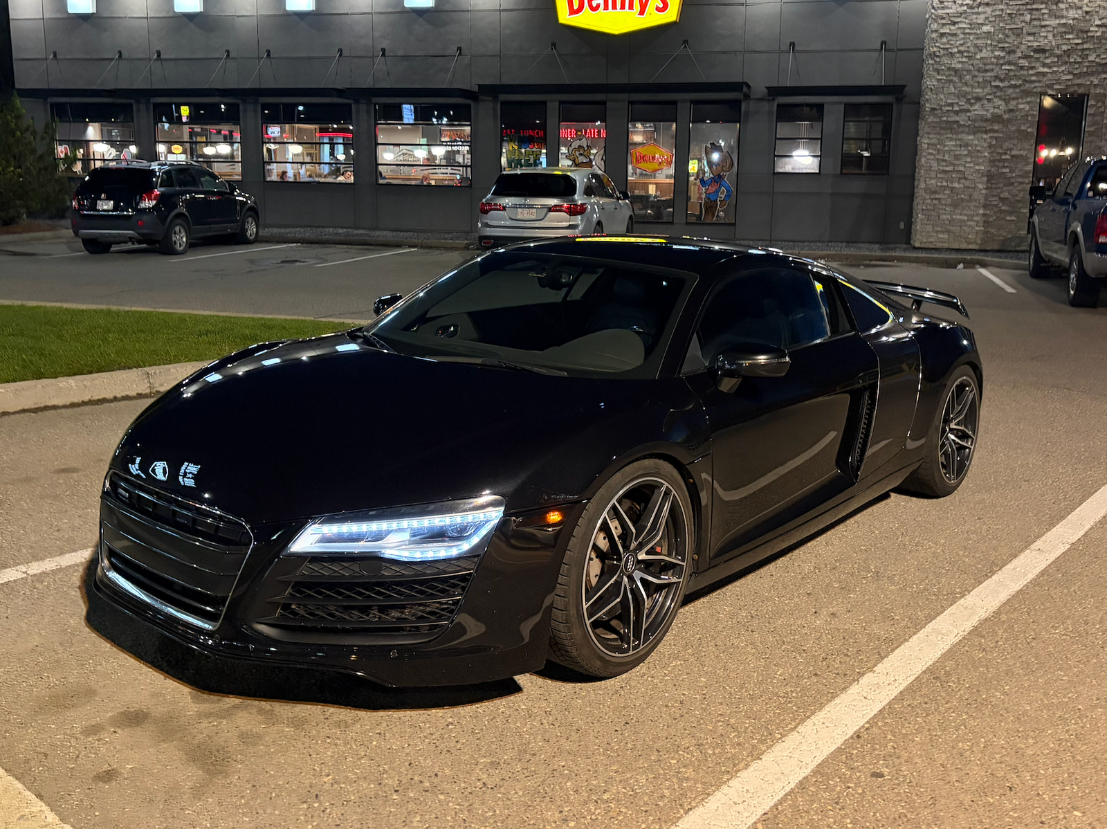 Black Audi R8 parked outside a restaurant at night