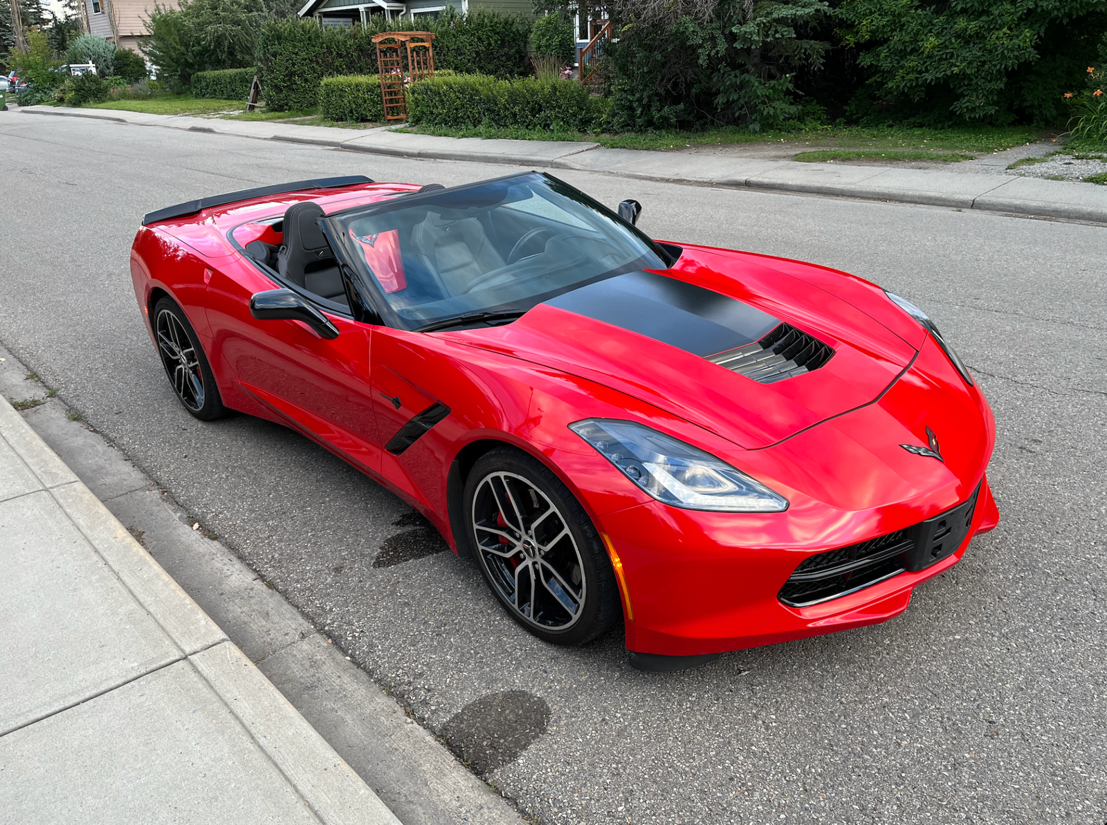 Red Chevrolet Corvette convertible parked on a residential street