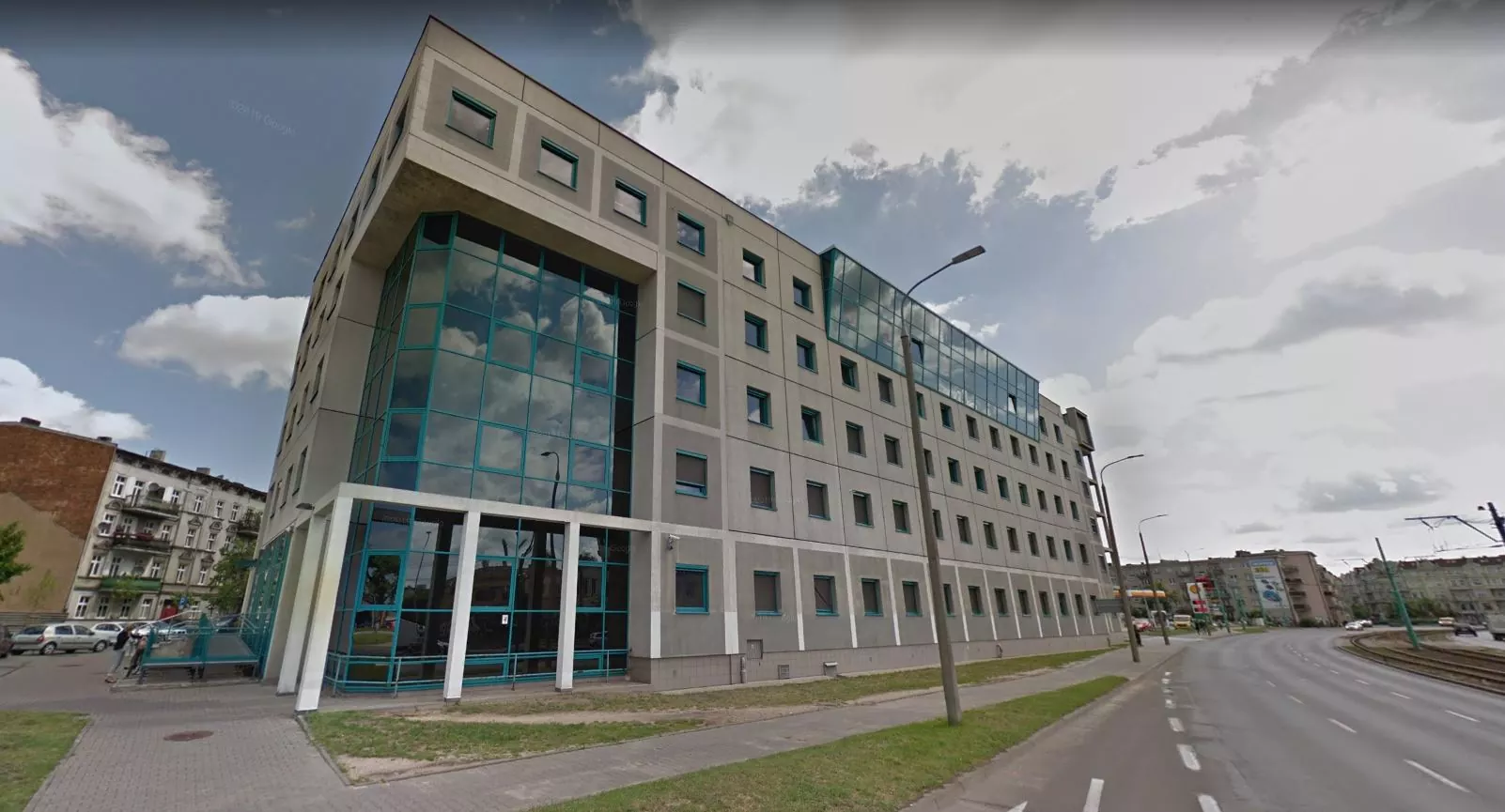 Nowoczesny budynek ZUS z szarą fasadą, dużymi oknami i turkusowymi akcentami