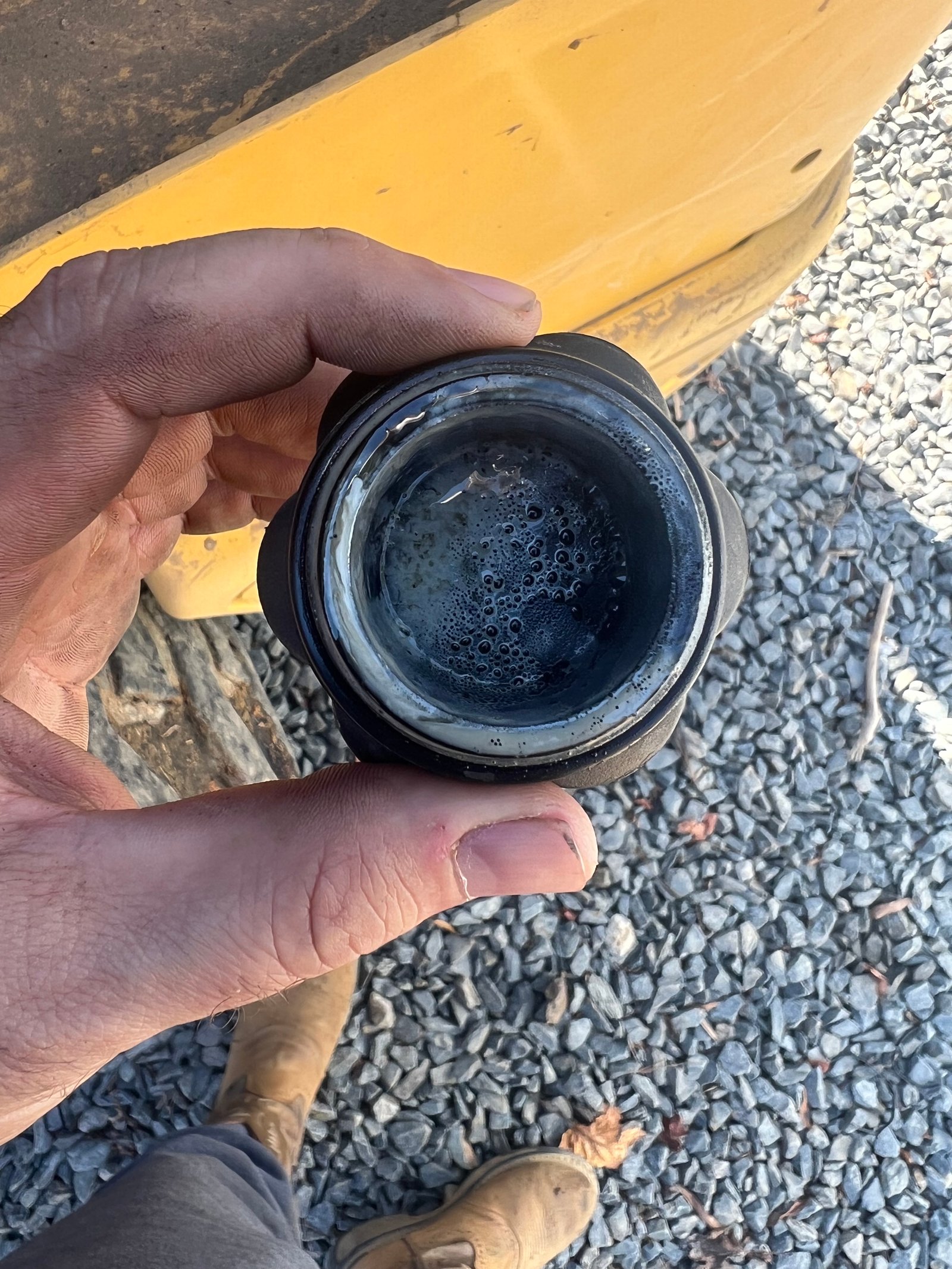 Oil filler cap from a New Holland L320 showing mayonnaise-like oil and coolant emulsion
