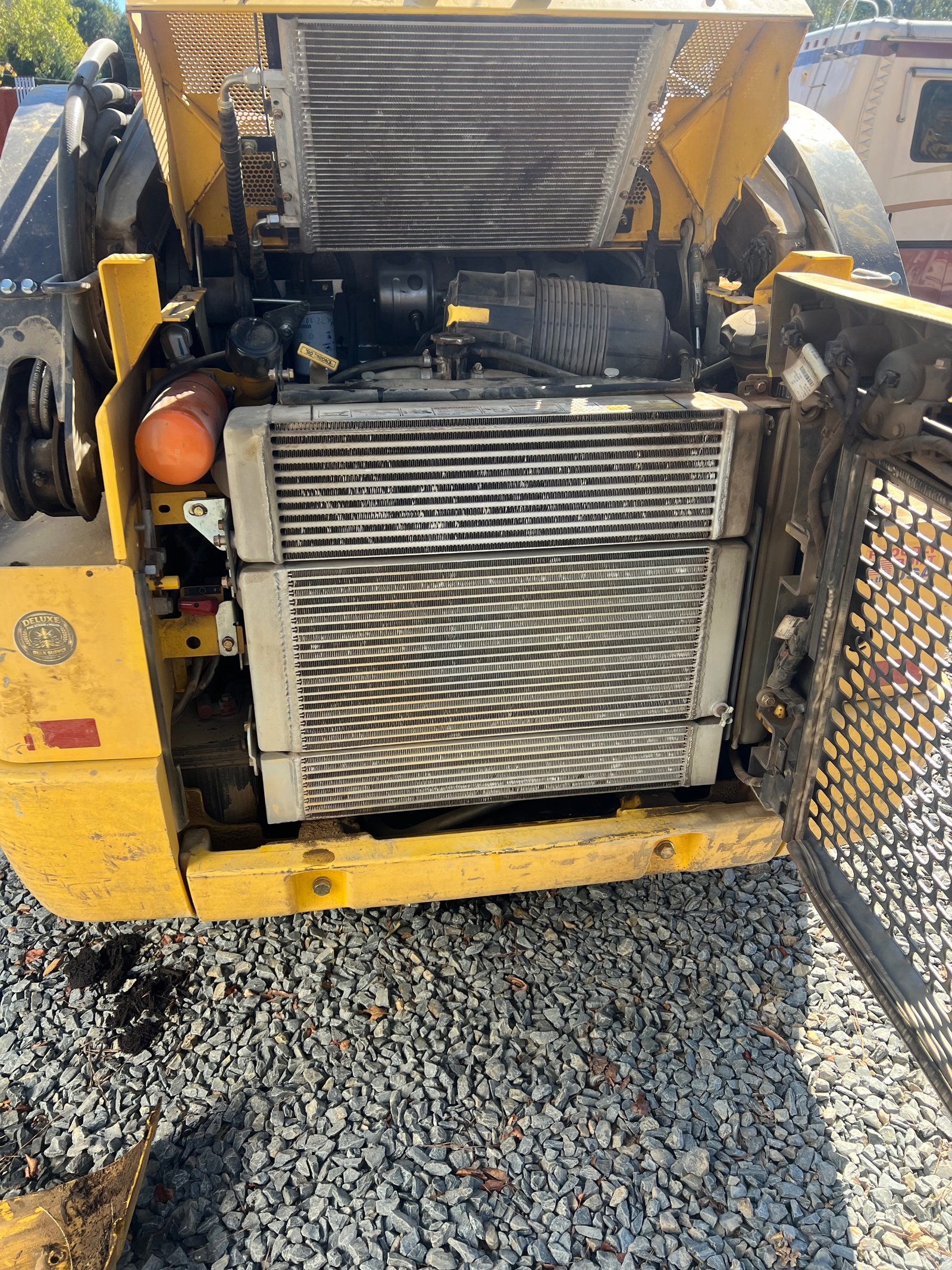 Cooling stack and radiator on a yellow New Holland L320 skid steer opened for oil cooler diagnosis