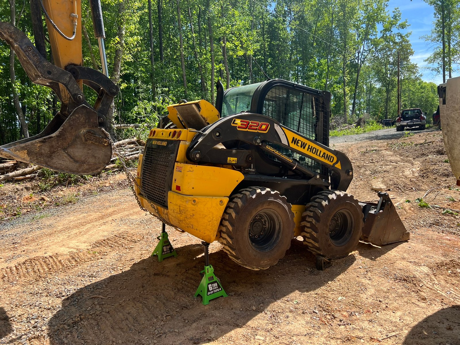 New Holland skid steer loader on job site with equipment in background
