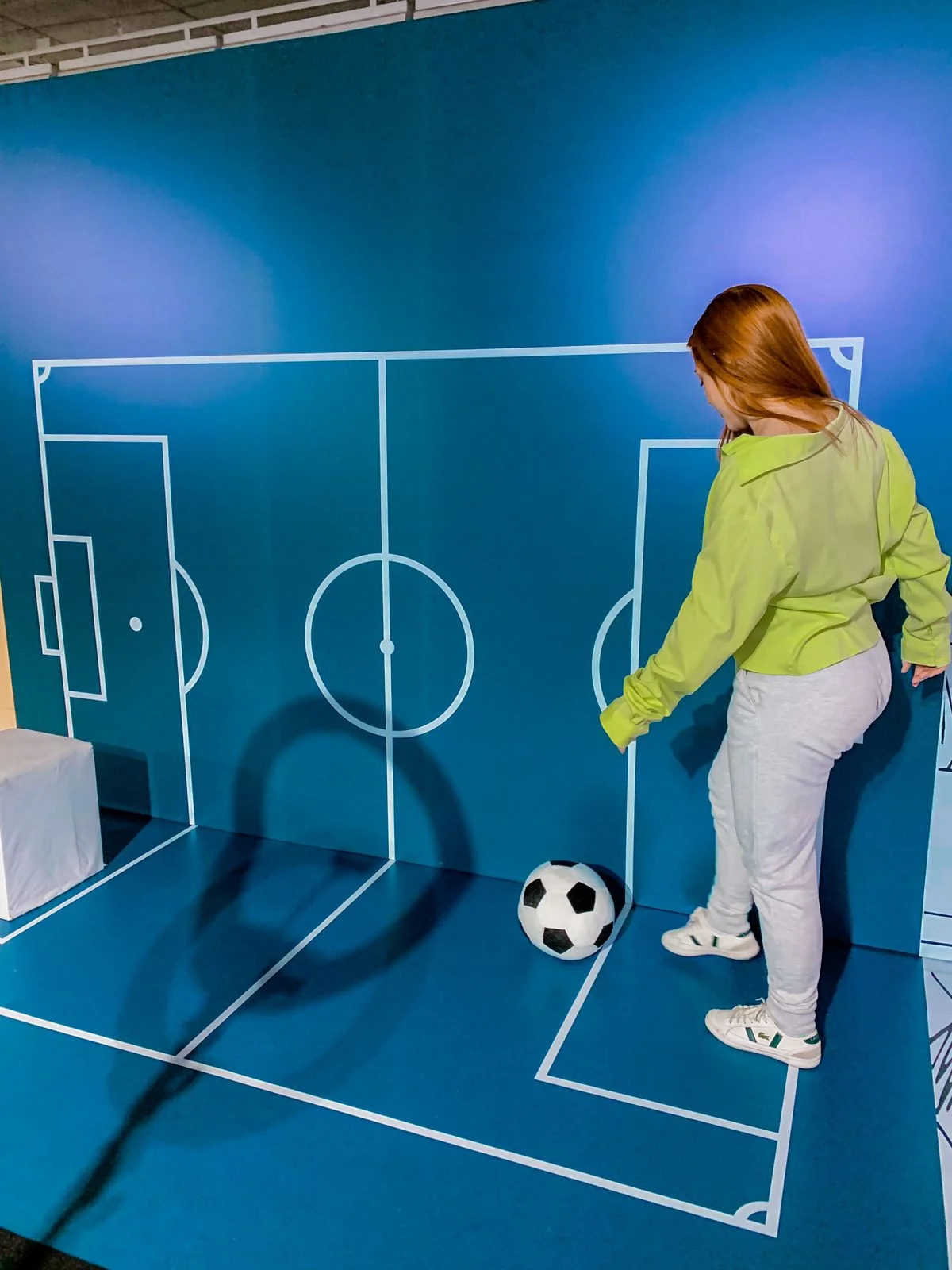 Visitante de jaqueta verde no cenário de campo de futebol em perspectiva