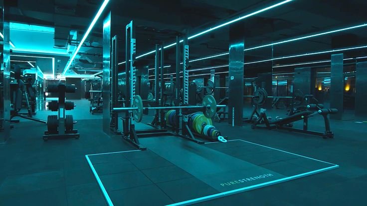 Premium gym facility with teal neon lighting and free weight equipment