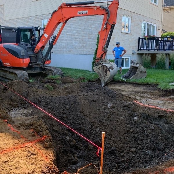 Excavatrice rouge creusant et préparant le terrain pour l'installation d'une piscine