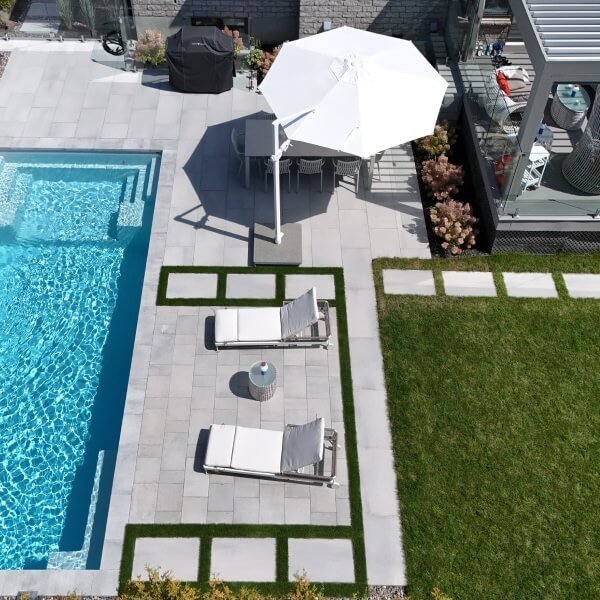 Vue aérienne piscine rectangulaire bleue avec terrasse en pavé