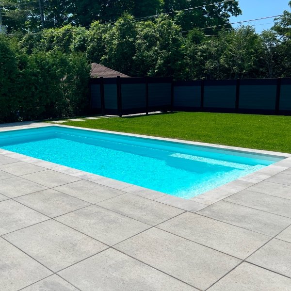 Piscine creusée moderne avec eau turquoise et pavés gris