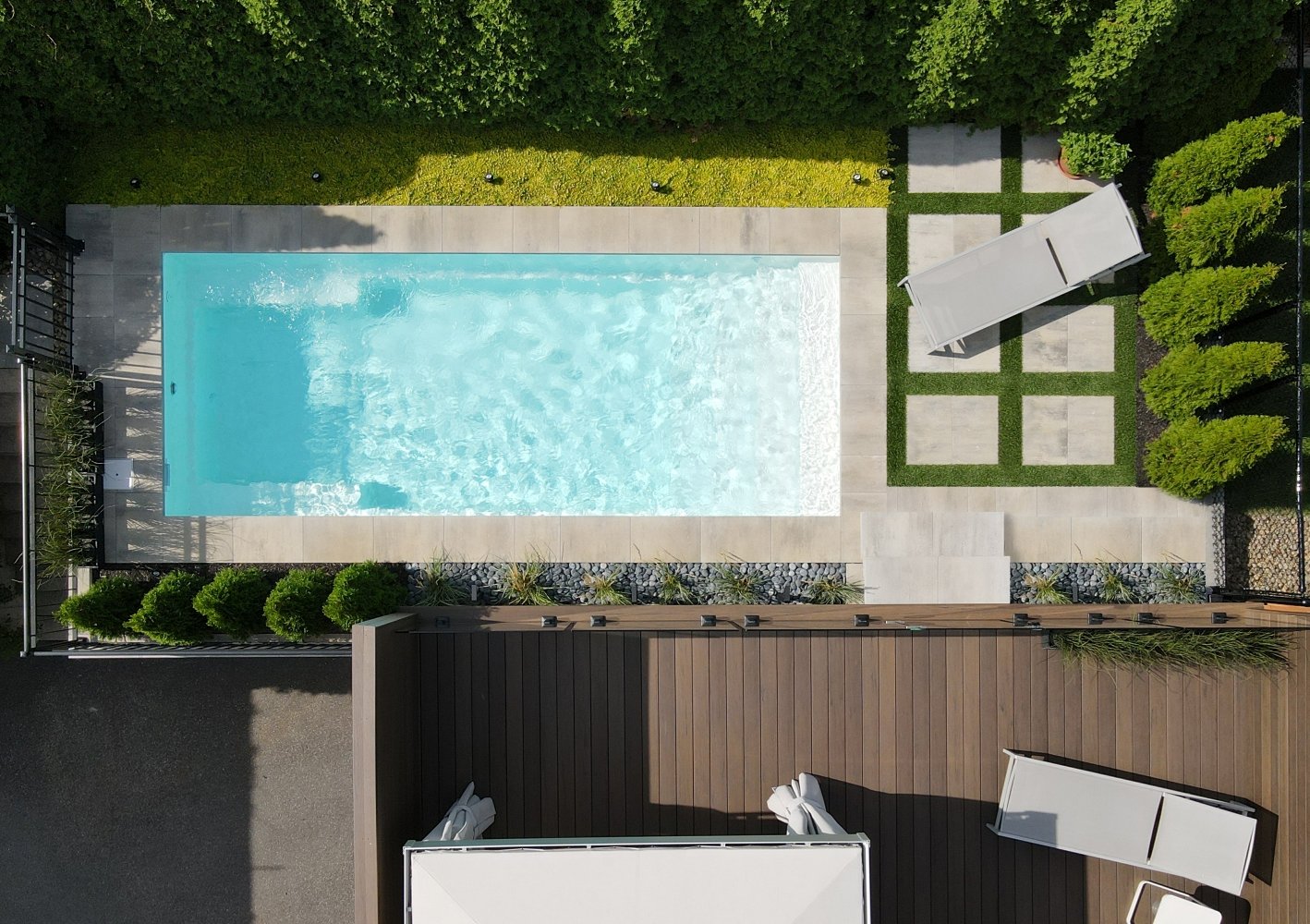 Aerial view of a full fiberglass inground pool with deck and landscaping