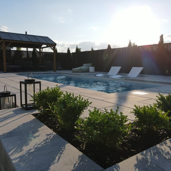 Rectangular pool with turquoise water, blue lounge chairs and green grass