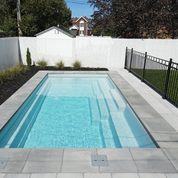 Piscine creusée entourée d'une clôture de sécurité conforme aux normes de Laval