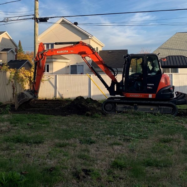 Excavatrice rouge Kubota préparant le terrain pour installation de piscine