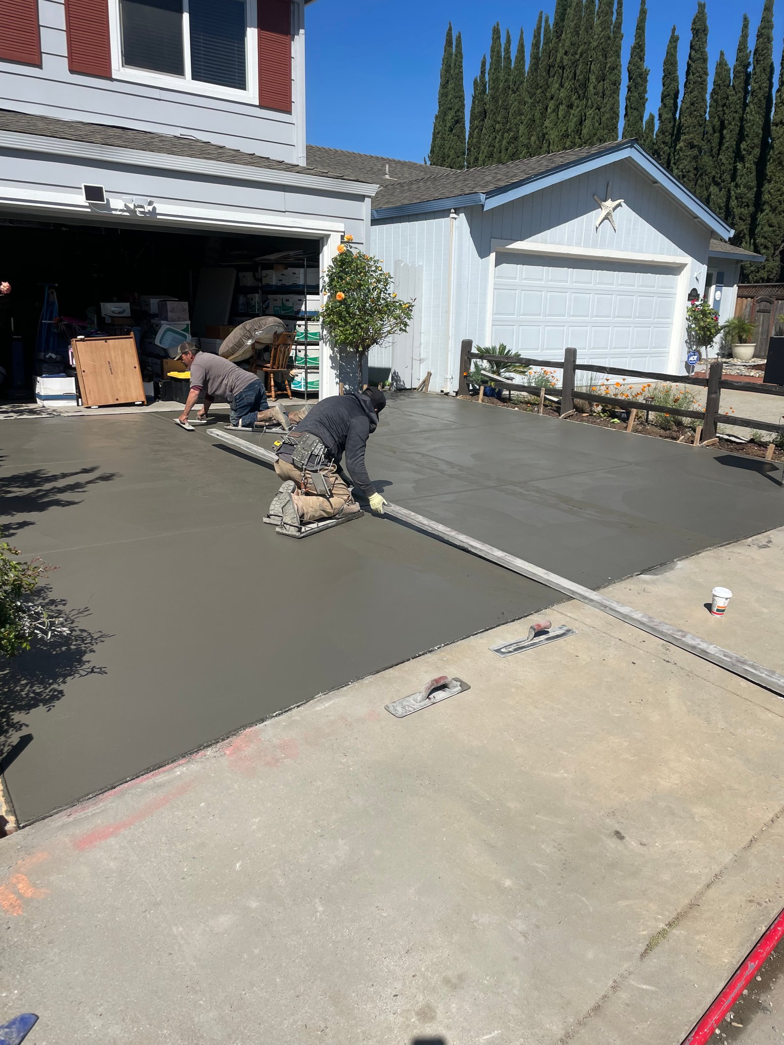 Concrete driveway being poured and finished with workers smoothing the surface