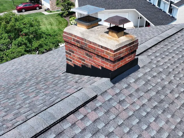 New shingles and flashing around a brick chimney on a finished roof in Middletown, Ohio