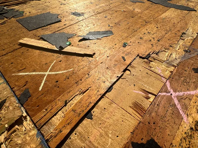 Damaged roof decking marked with an X for replacement during a tear-off in New Carlisle, Ohio
