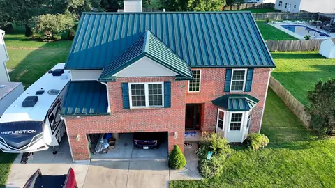 Front elevation of a Xenia, Ohio brick home with standing-seam metal roof over the bay window and porch