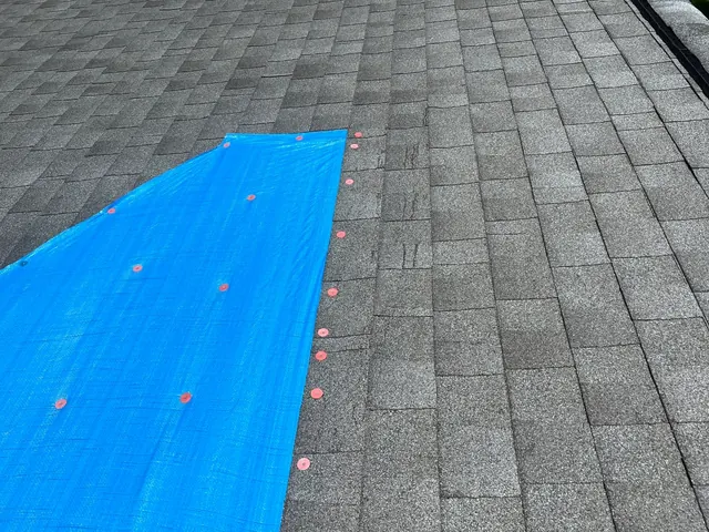 Blue tarp fastened over a damaged roof section as a temporary cover in Tipp City, Ohio