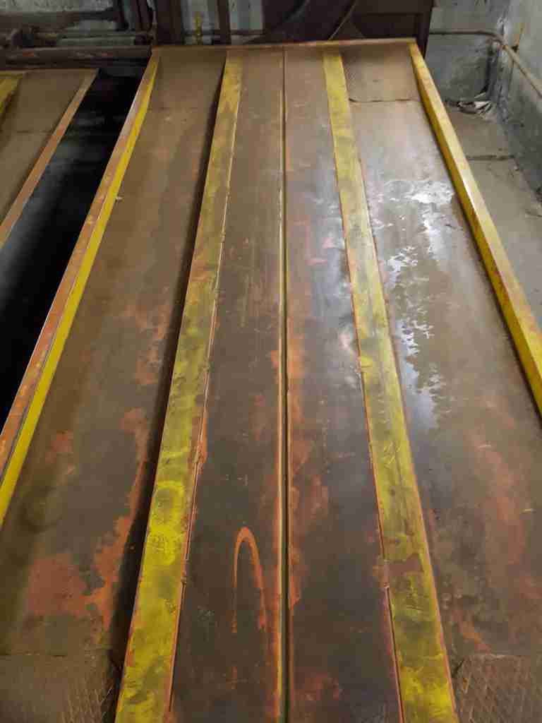 Intérieur du parking automatique avant rénovation - plateformes jaunes et rouges rouillées, murs sales, éclairage insuffisant