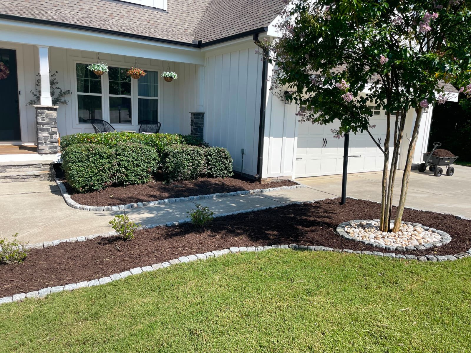 Fresh mulch beds with shrubs and clean edging along driveway