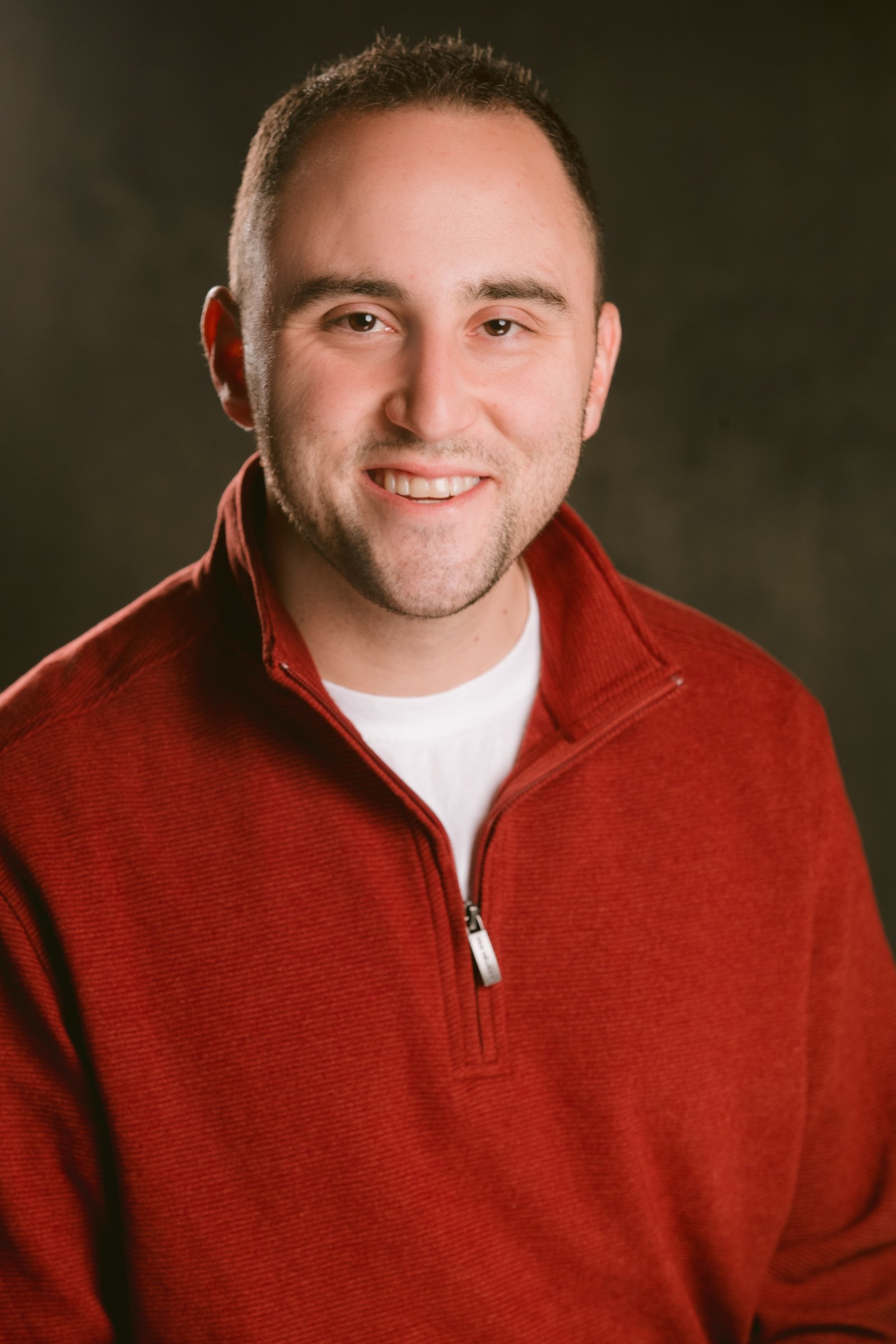 Adam Joseph Turner studio headshot in a red quarter-zip