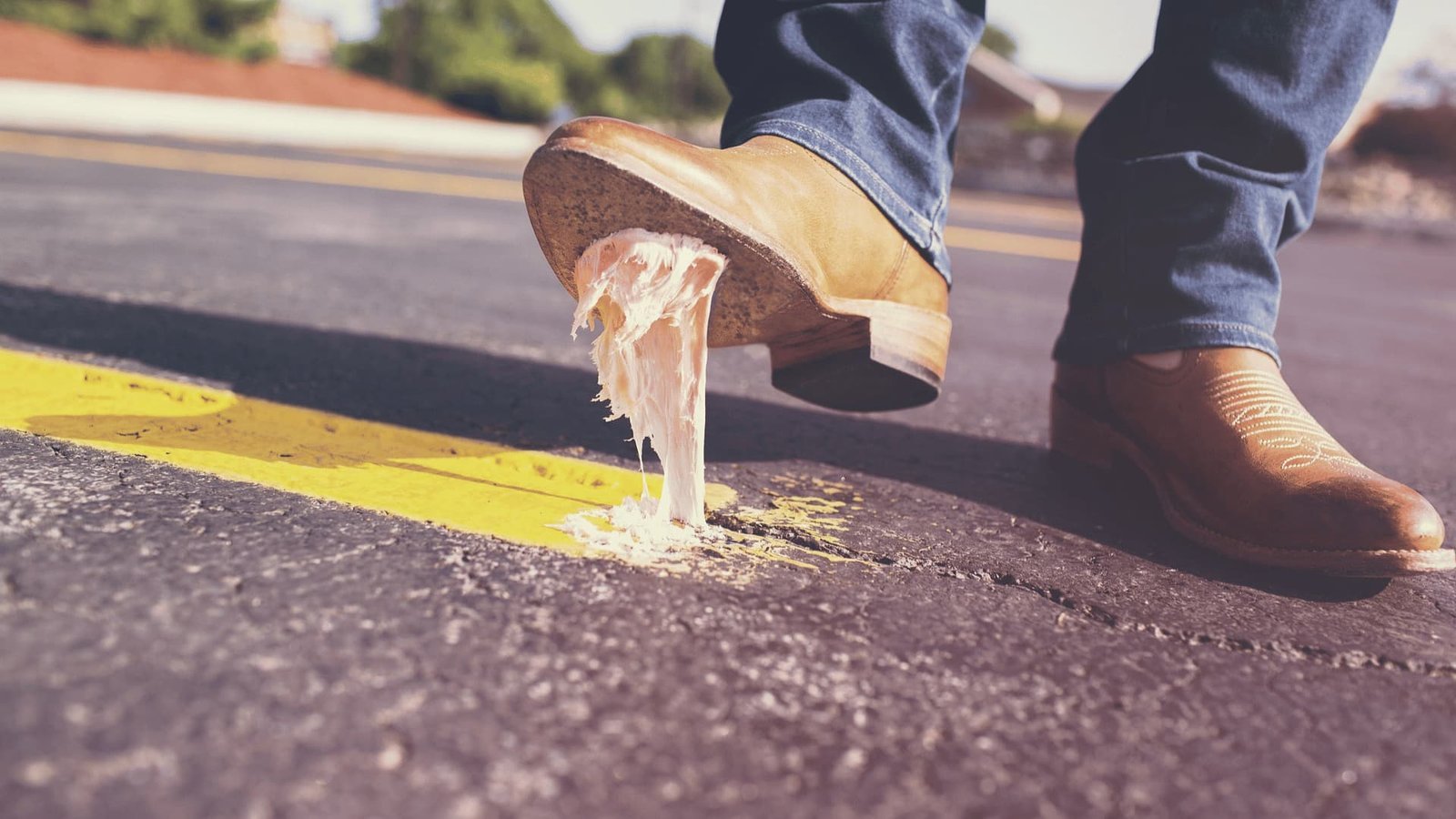 Cowboy boots on asphalt road with yellow line