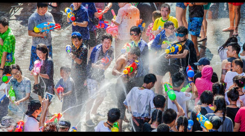 Authentic Songkran water festival street celebration with colorful water guns and dense crowd