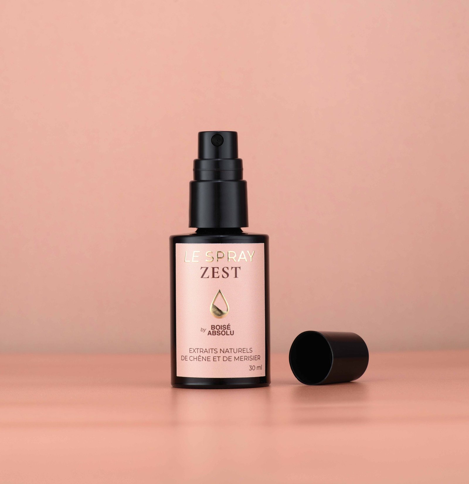 Flacon LE SPRAY ZEST, capuchon posé à côté, sur fond rose