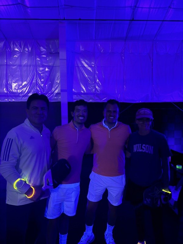 Four people in neon-lit padel facility