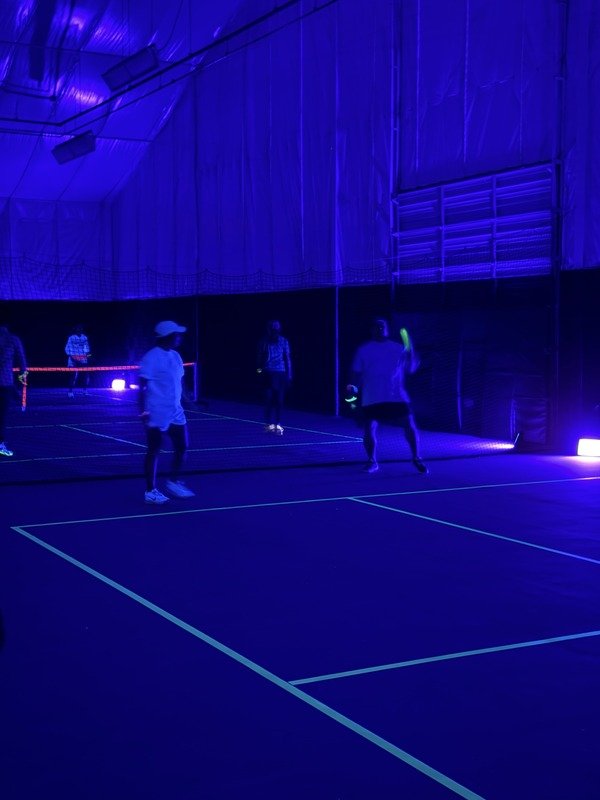 Players on neon purple padel court