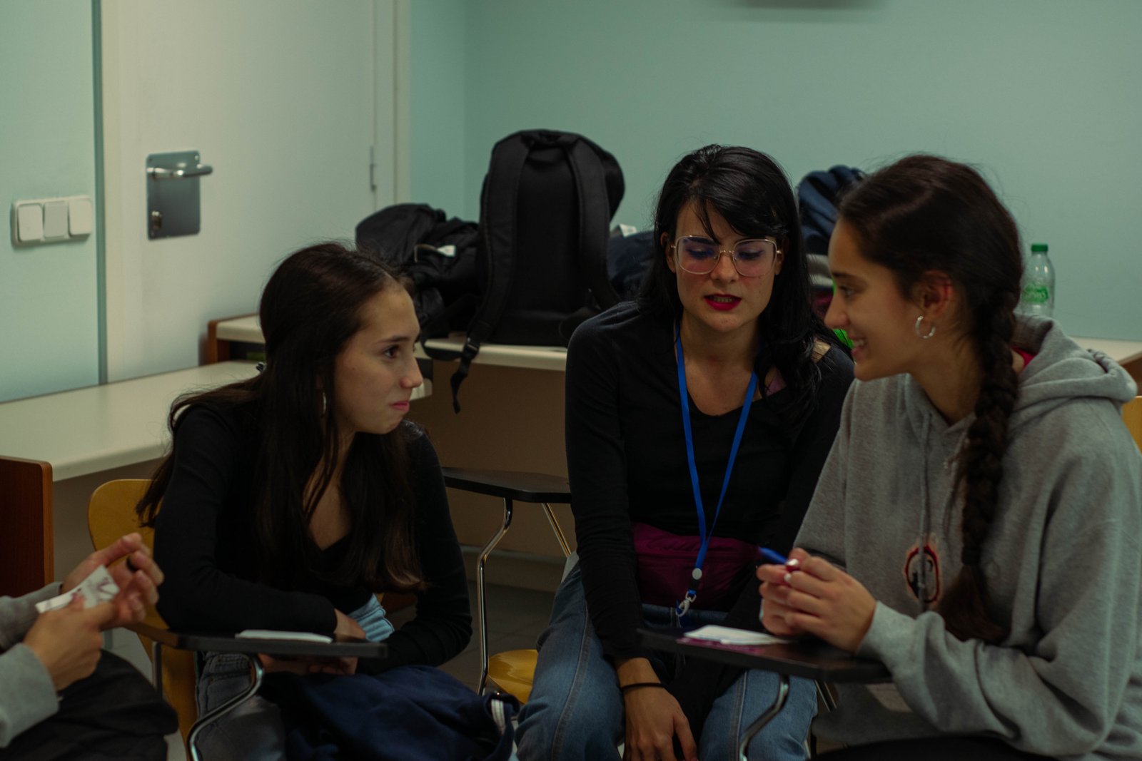 Tres mujeres conversan en un aula durante una actividad educativa