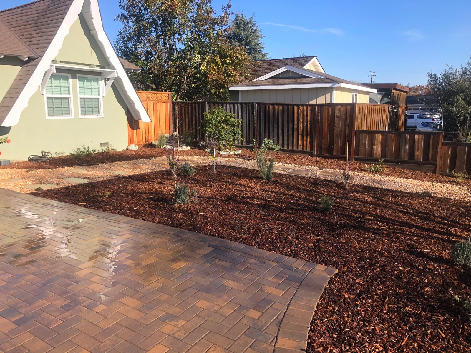 Finished concrete patio with herringbone pattern, wooden fence, and landscaping