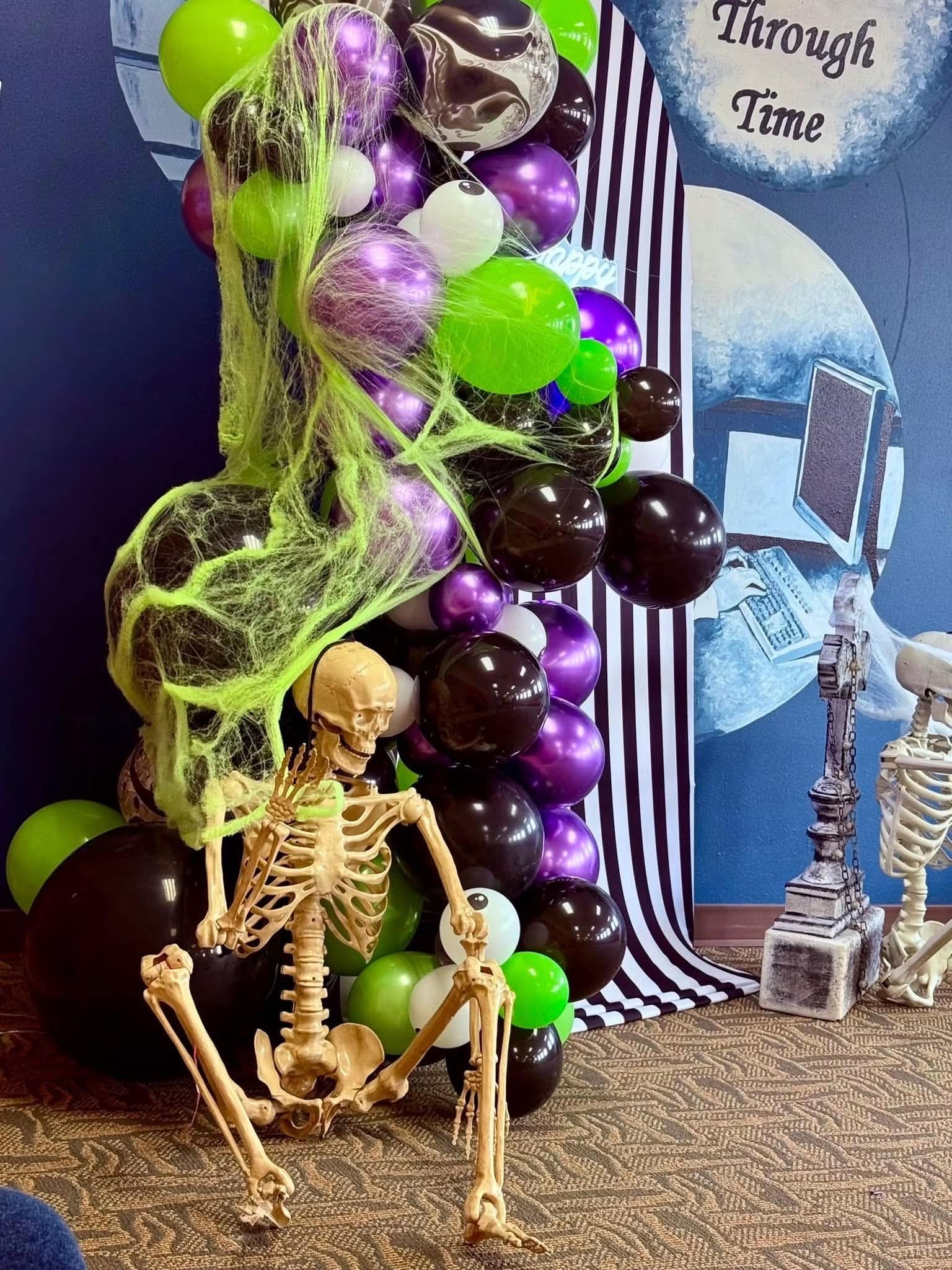 Close-up of a Halloween balloon column with cobwebs and a skeleton
