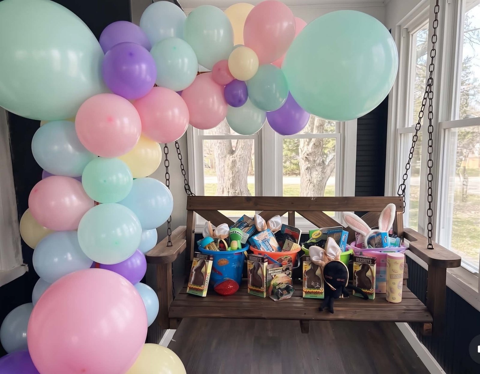 Pastel balloon garland over a treat table filled with colorful party favors