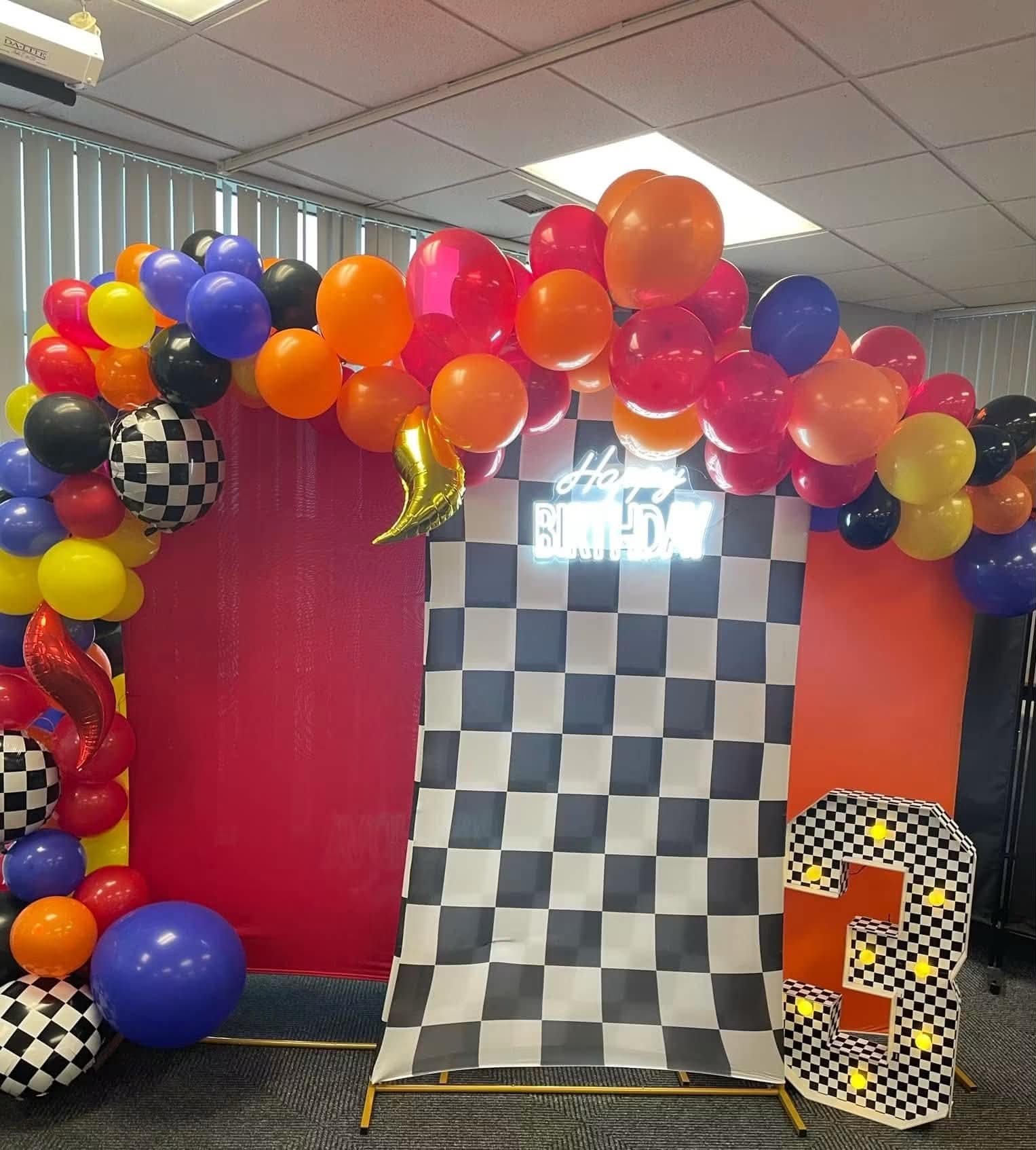 Bright race-car balloon arch with checkered backdrop and light-up number two