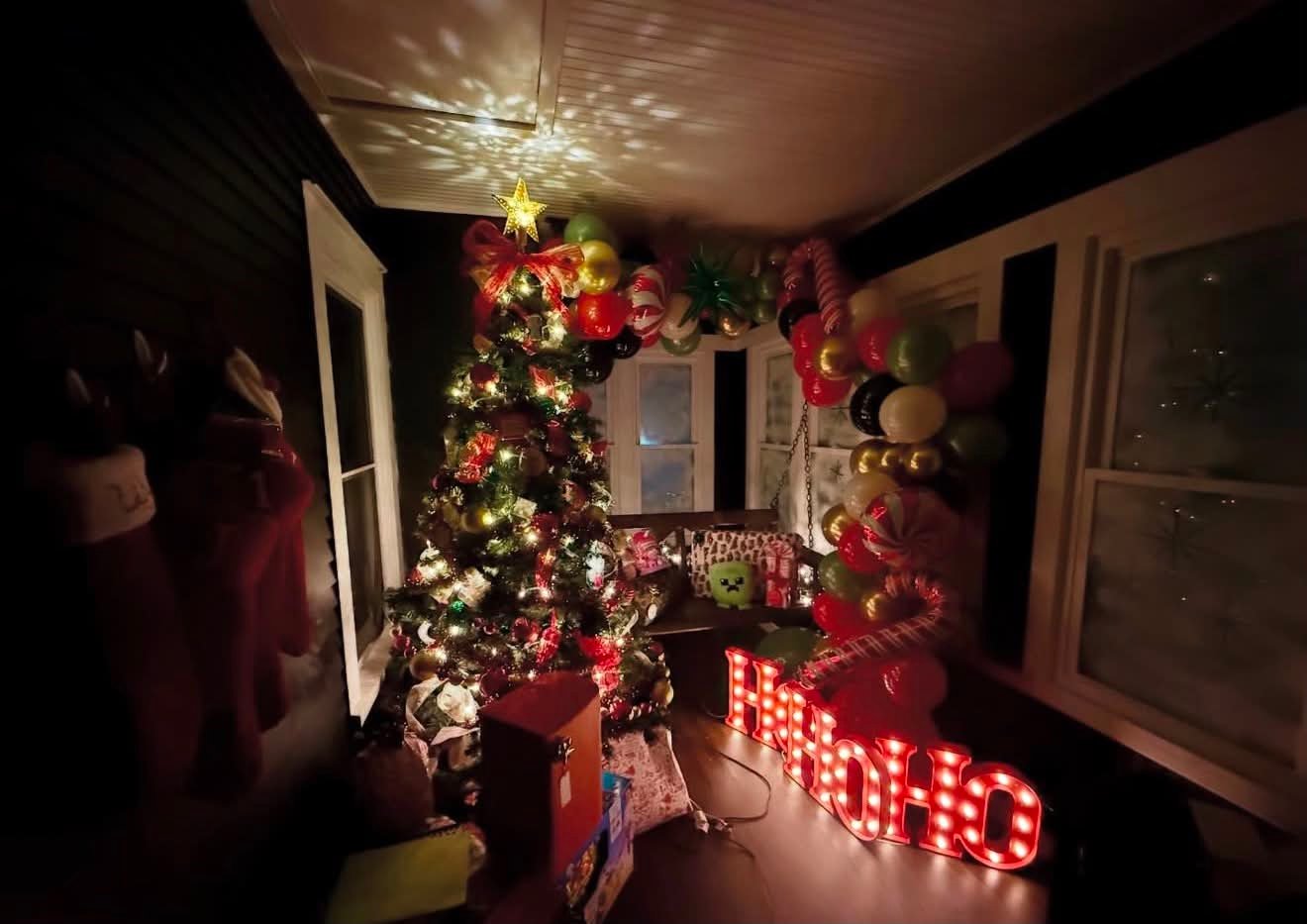 Christmas event setup with lit tree, candy-cane balloon garland, and glowing HOHOHO marquee letters