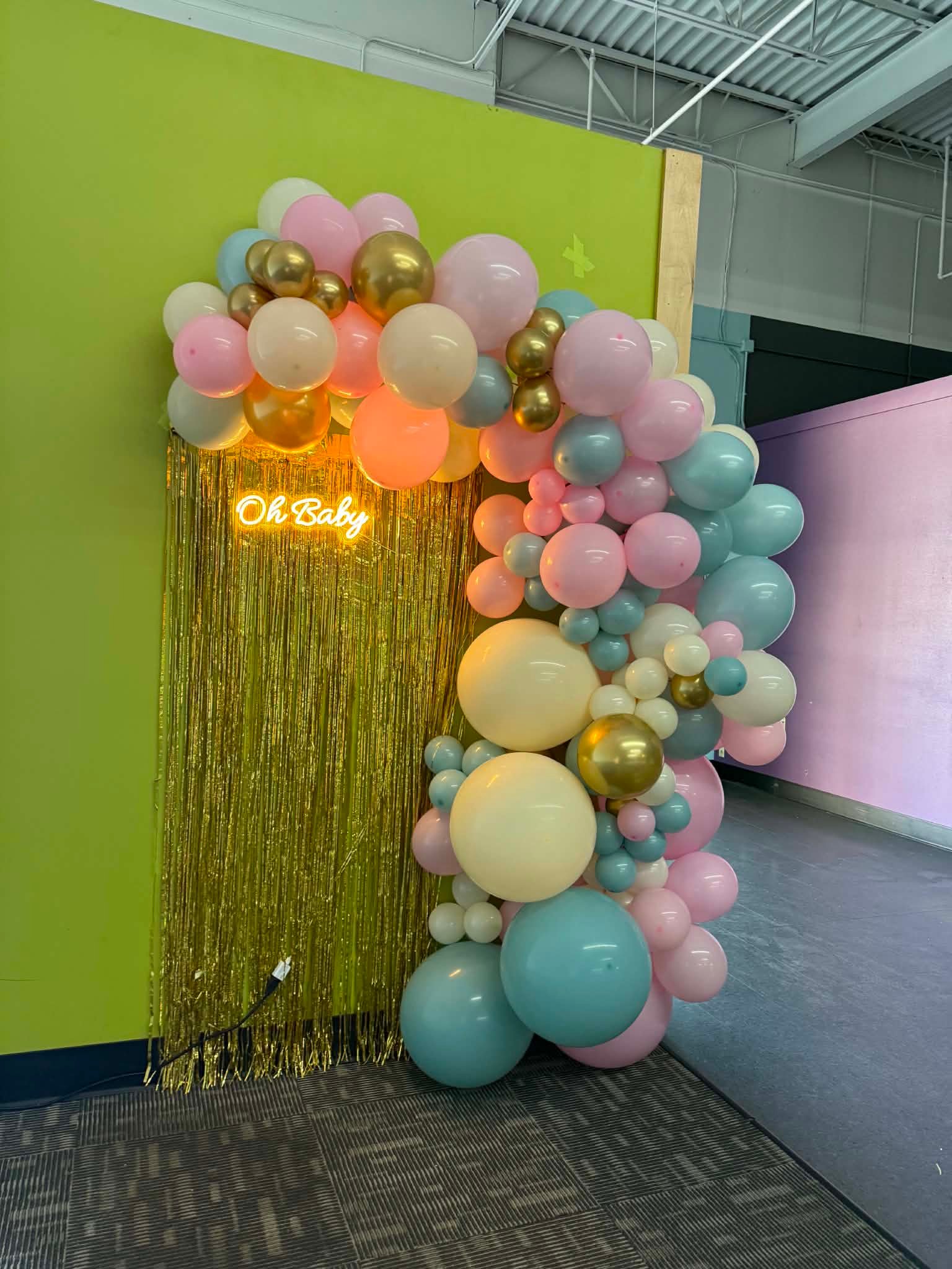Pastel pink, blue and gold balloon garland framing an Oh Baby neon sign