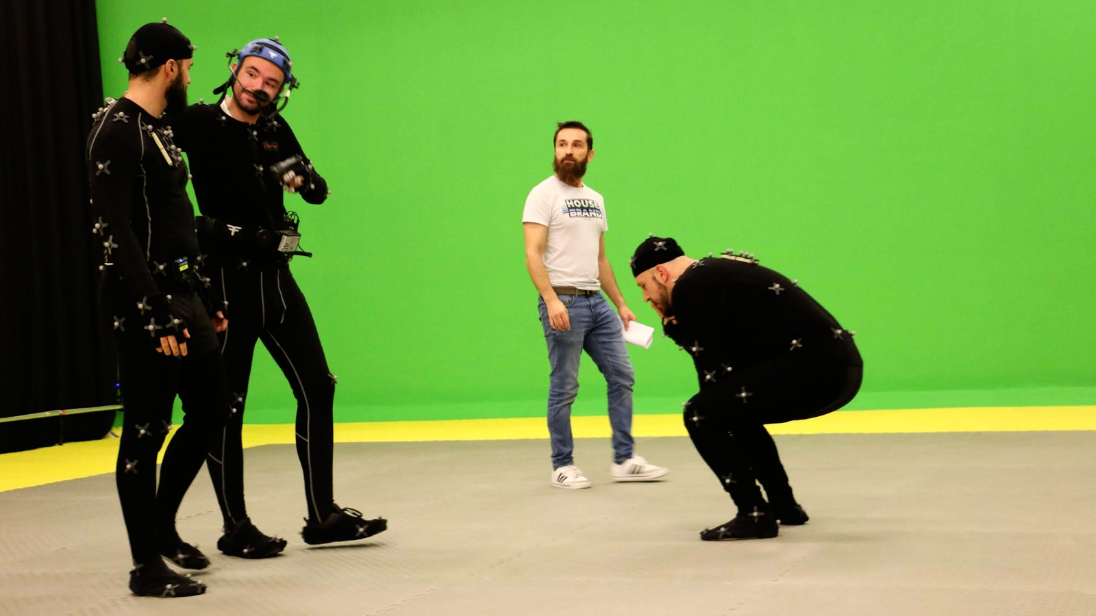 Performers in motion capture suits on a green screen set