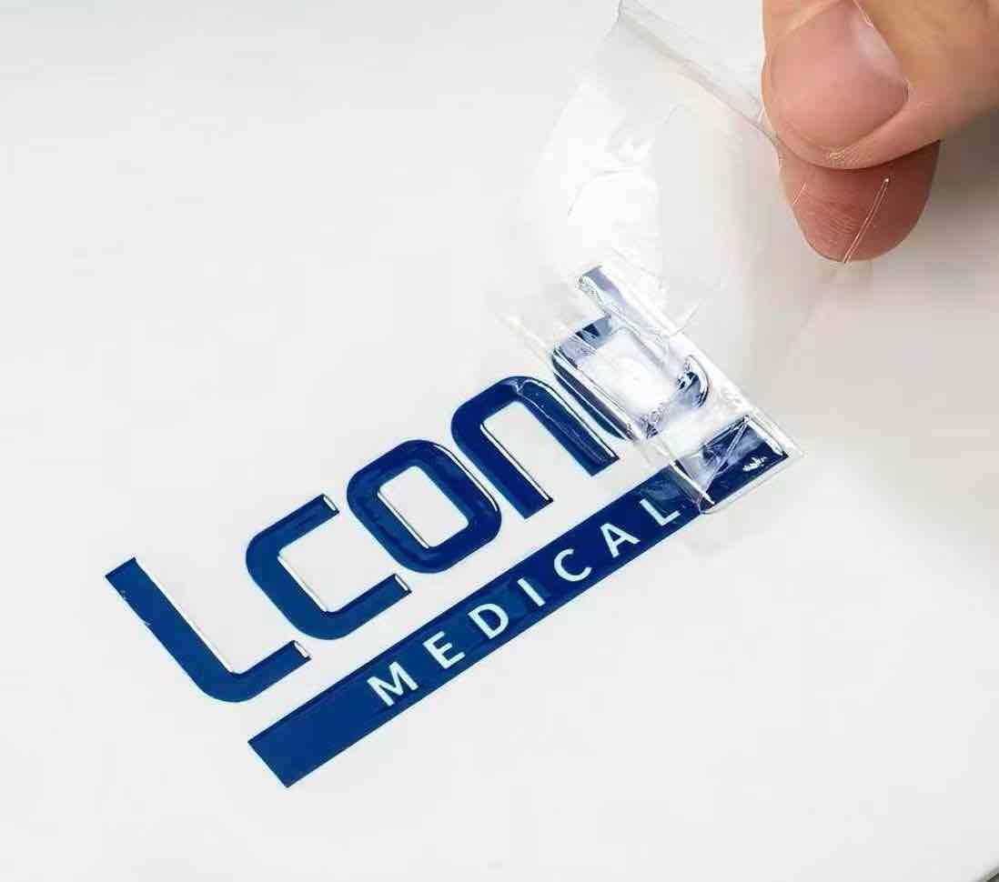 Adhesive sticker label on a white product with a blue logo, being peeled off.