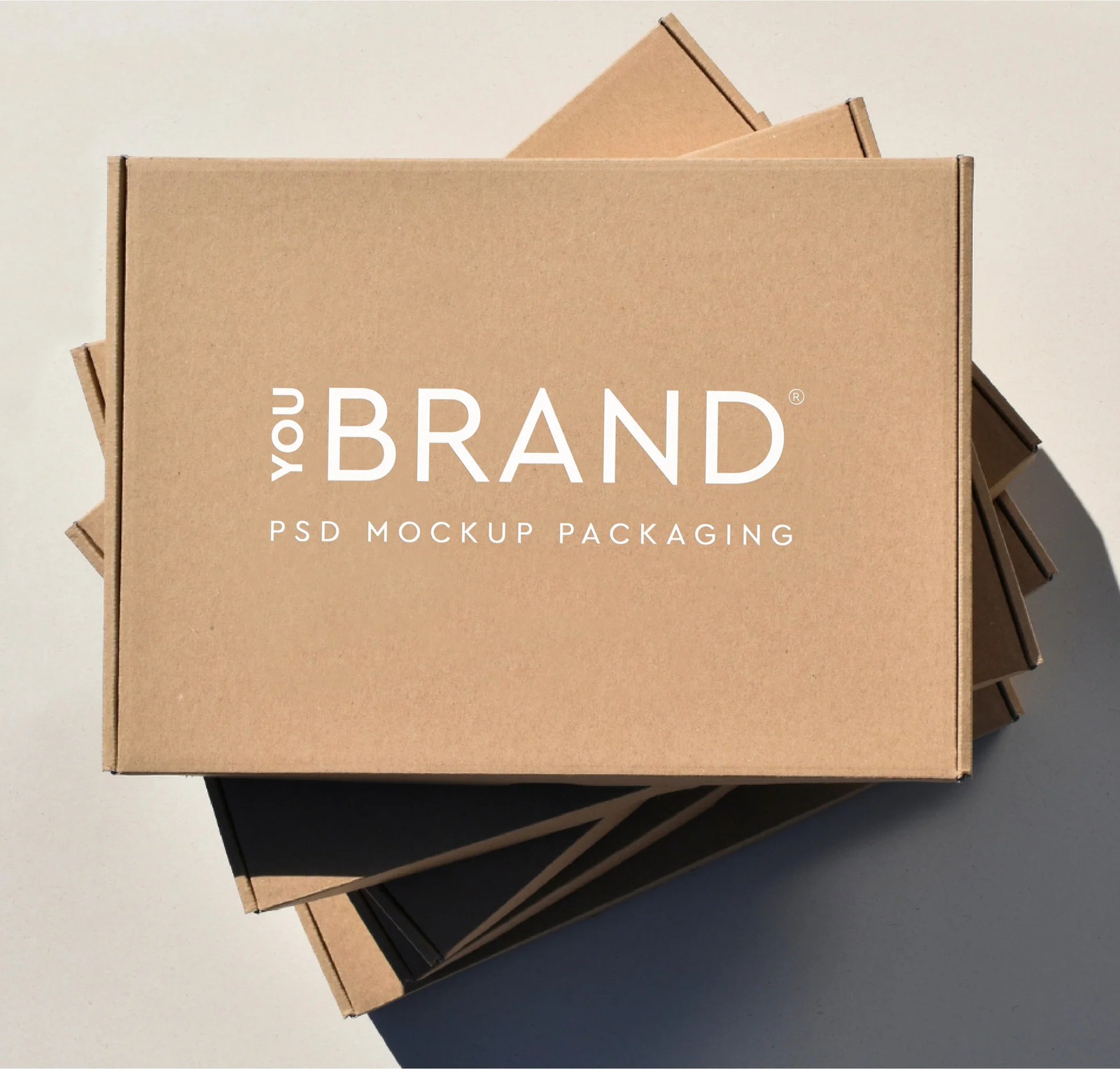 Stack of plain cardboard boxes with a white 'YOUR BRAND PSD MOCKUP PACKAGING' logo on the top box.