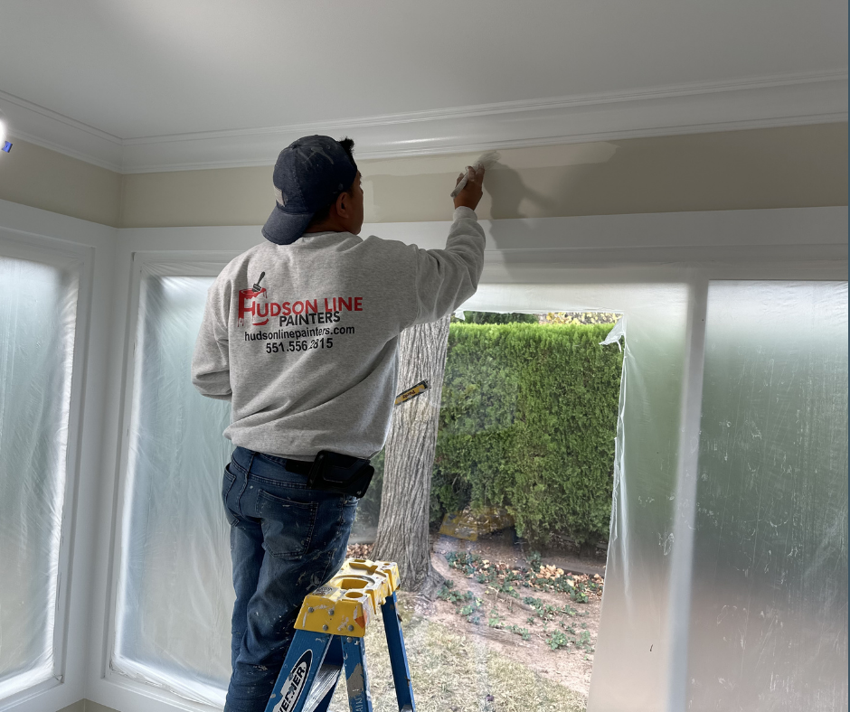 Hudson Line Painters professional painting interior wall and trim near a window from a ladder during interior painting preparation
