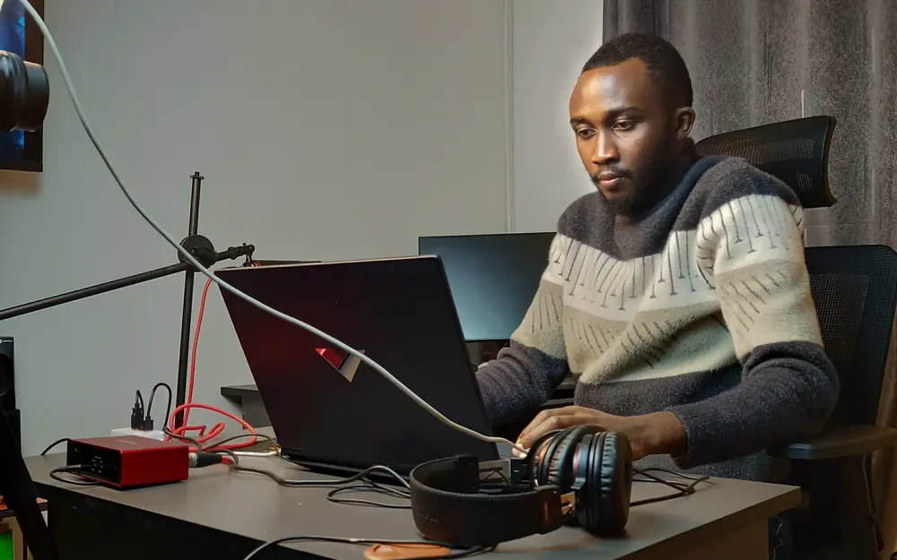 Elvis working in a production studio setup with headphones and laptop.