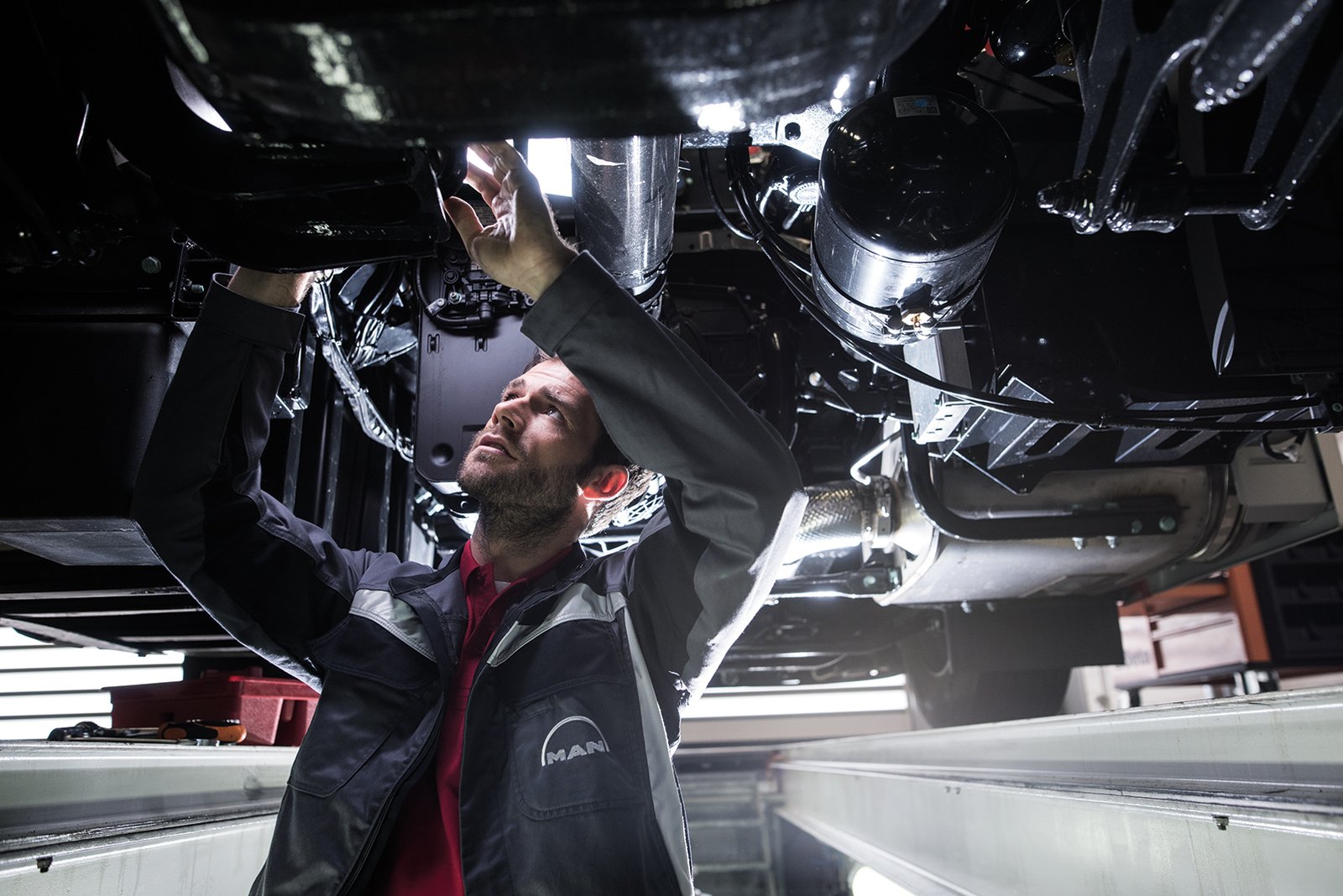MAN-Techniker prüft das Fahrwerk eines Nutzfahrzeugs in der Werkstattgrube