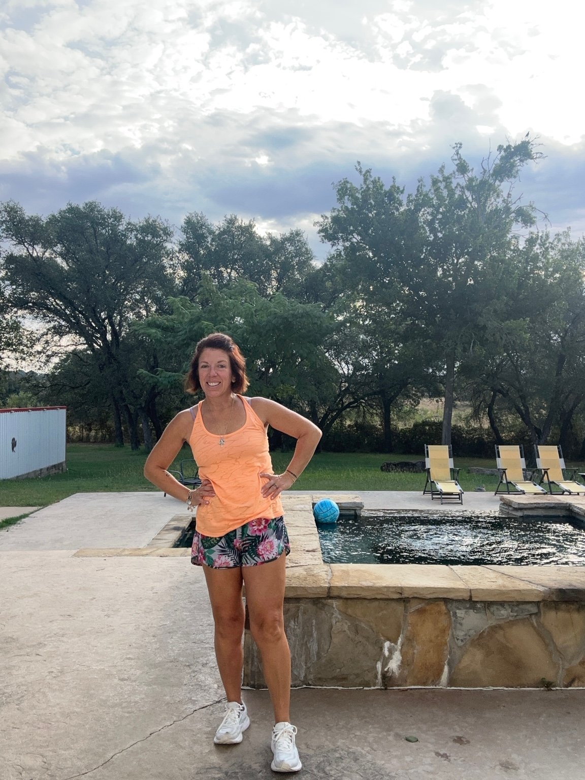 Jennifer standing beside a pool with her hands on her hips