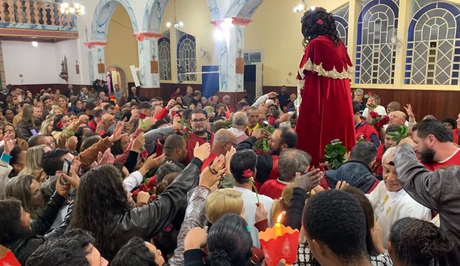 Fiéis estendem as mãos em direção à imagem do Bom Jesus dentro da Basílica