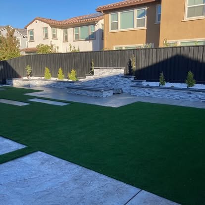 Large concrete retaining wall with patio and green lawn