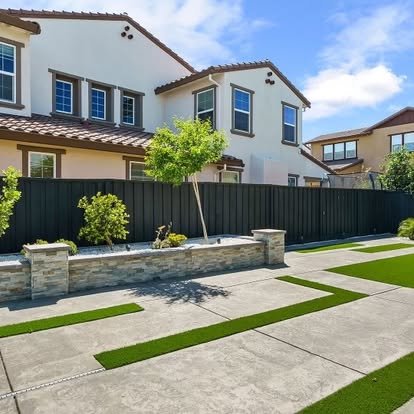 Modern concrete patio with stone retaining wall and artificial turf