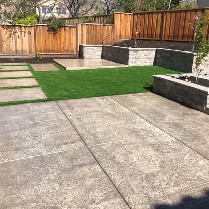 Concrete patio with retaining wall and green lawn