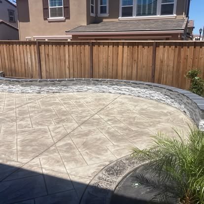 Curved concrete patio with retaining wall and landscaping