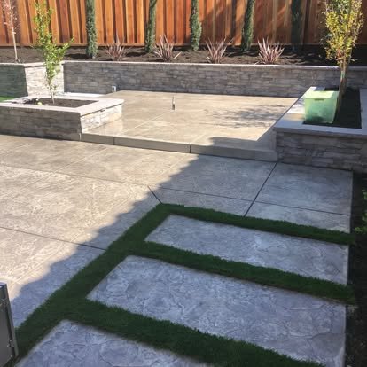 Large concrete patio with stepping stones and green lawn